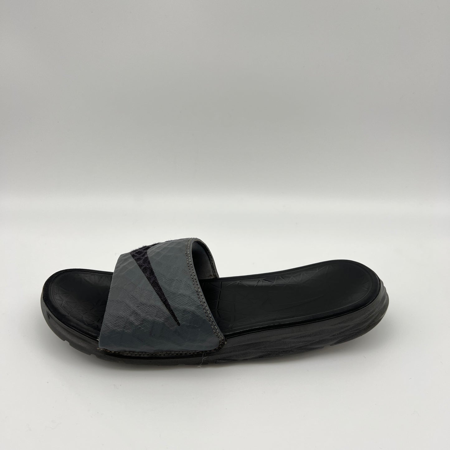 Nike Benassi Solarsoft 2 slide in grey and black featuring a textured, fractal-patterned strap with a black Swoosh and a contoured black footbed.