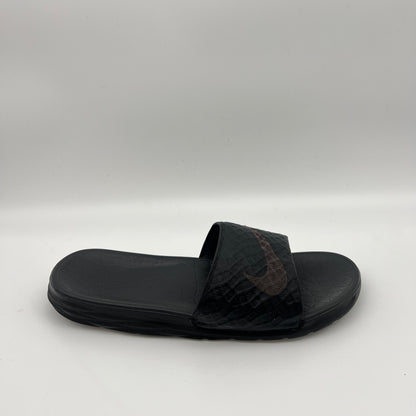 Side view of a triple black Nike Benassi Solarsoft slide with a geometric-patterned strap, a subtle dark swoosh logo, and a textured comfort footbed.