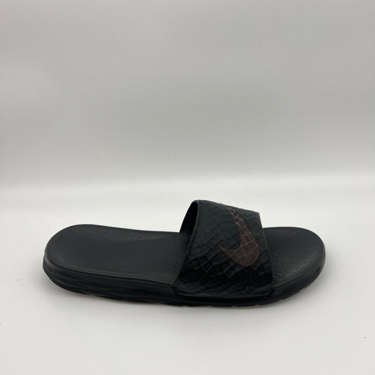 Side view of a triple black Nike Benassi Solarsoft slide with a geometric-patterned strap, a subtle dark swoosh logo, and a textured comfort footbed.