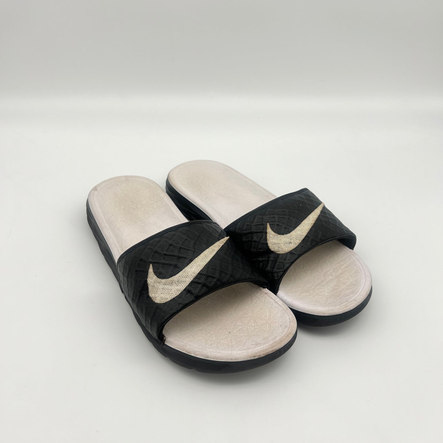 Black and beige Nike slides on a light gray background