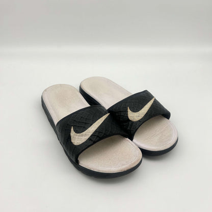 Black and beige Nike slides on a light gray background