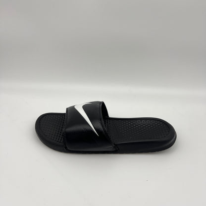 Side profile of a black Nike Benassi Swoosh slide sandal featuring a large white iconic logo on the strap and a textured footbed on a white background.