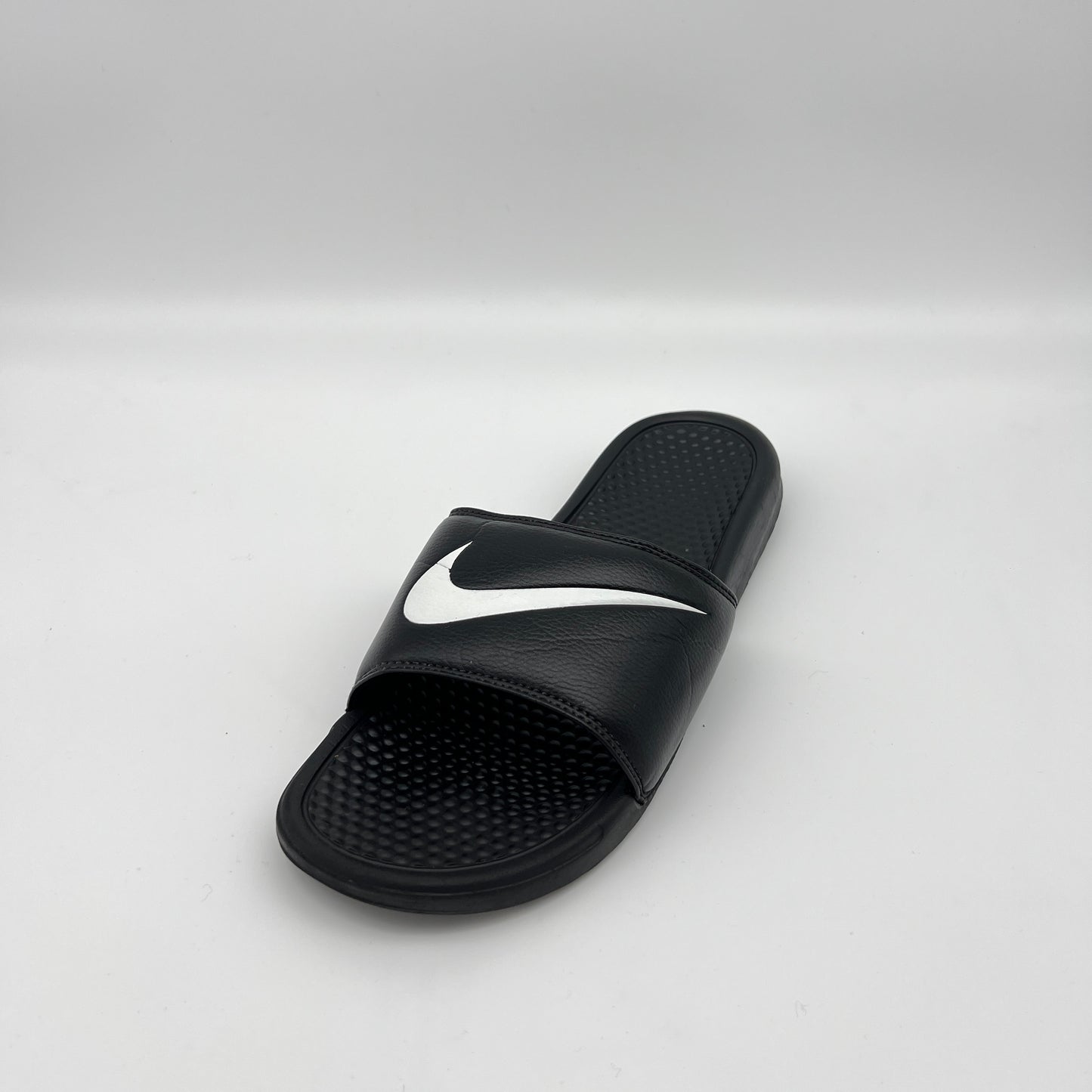 Black slide sandal with a white logo on a light gray background