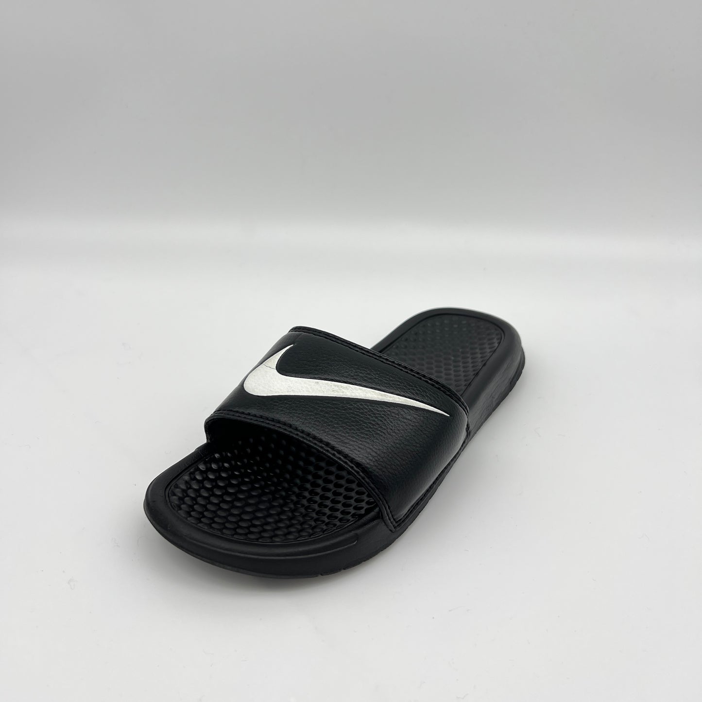 Black slide sandal with a white logo on a light gray background