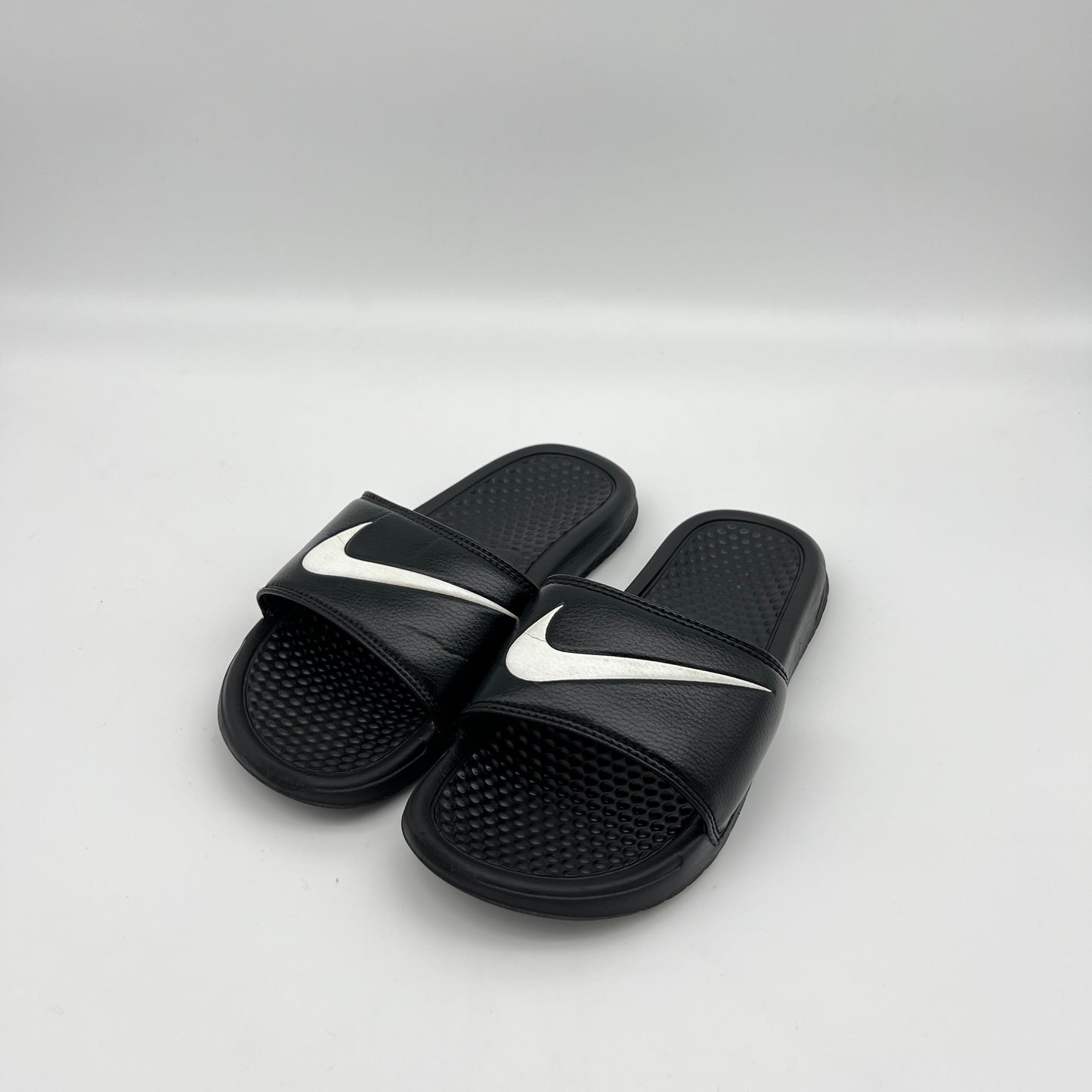 Black slides with white swoosh logo on a light gray background