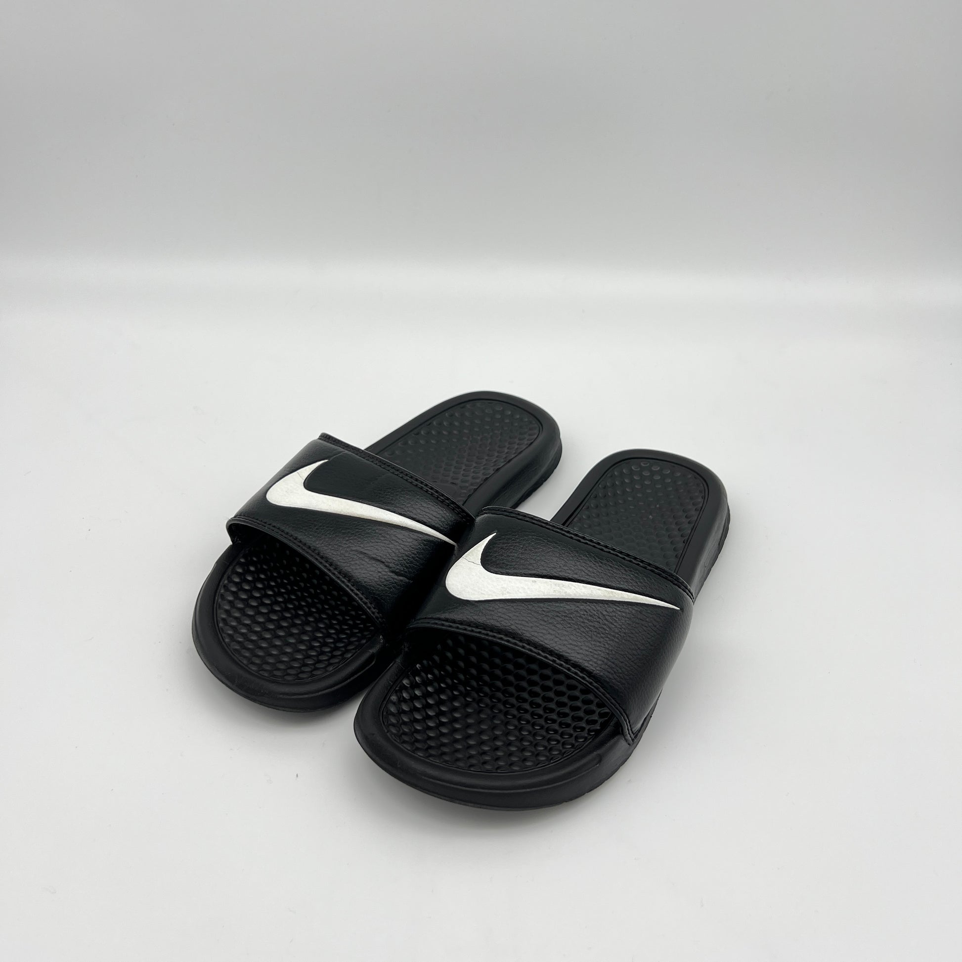 Black slides with white swoosh logo on a light gray background