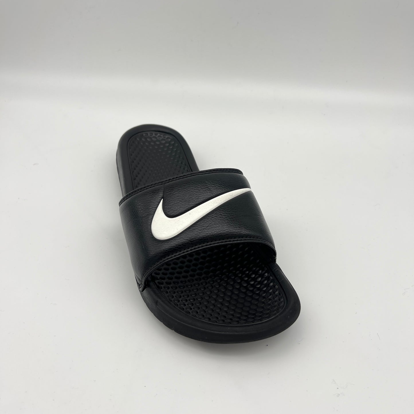 Black slide sandal with white Nike logo on a light gray background
