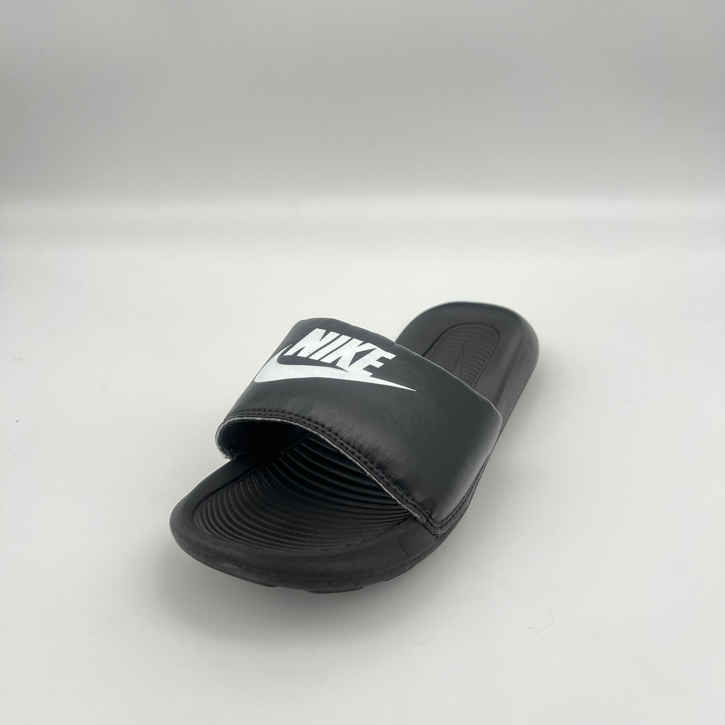 Black Nike slide sandal on a light gray background