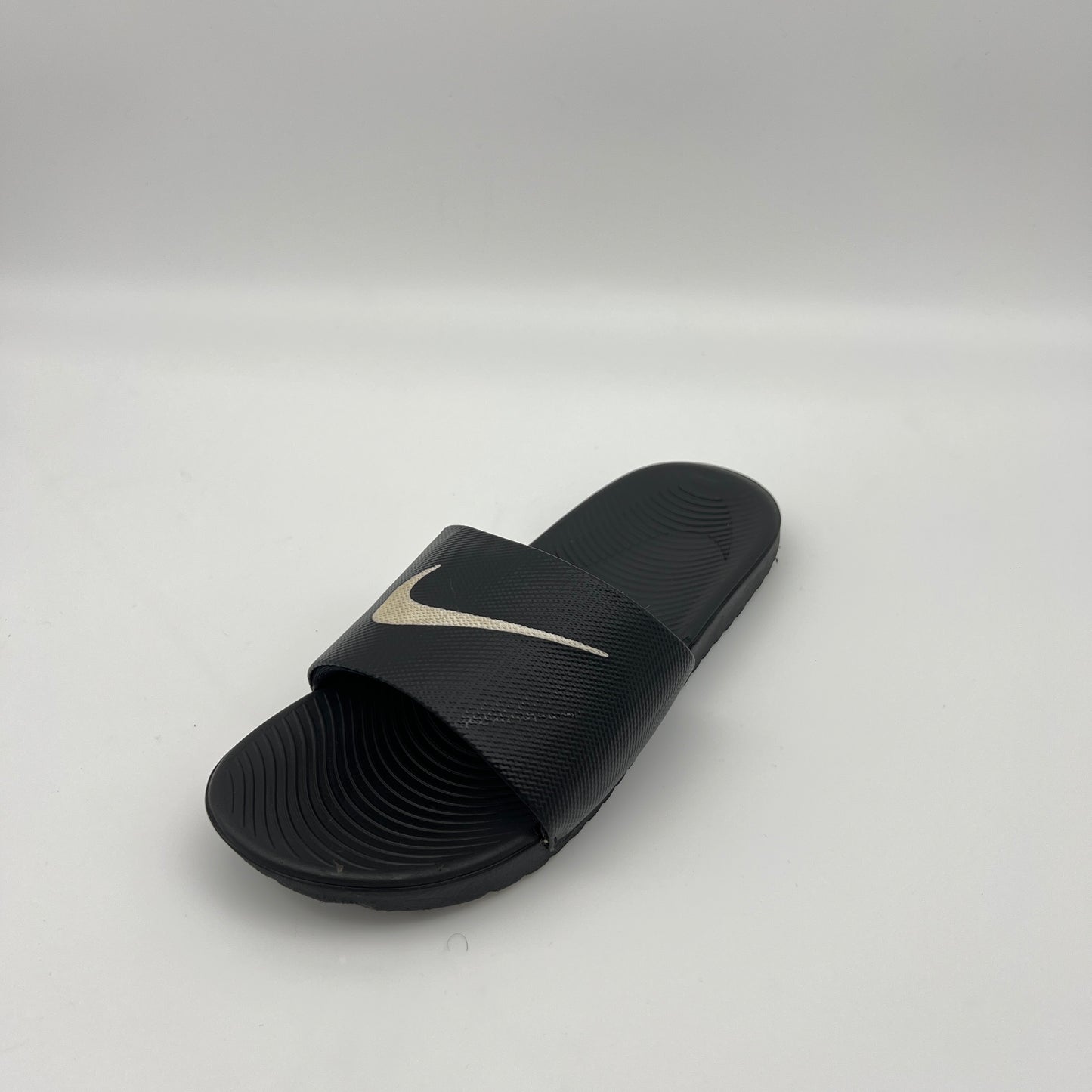 Black slide sandal with a logo on a light gray background