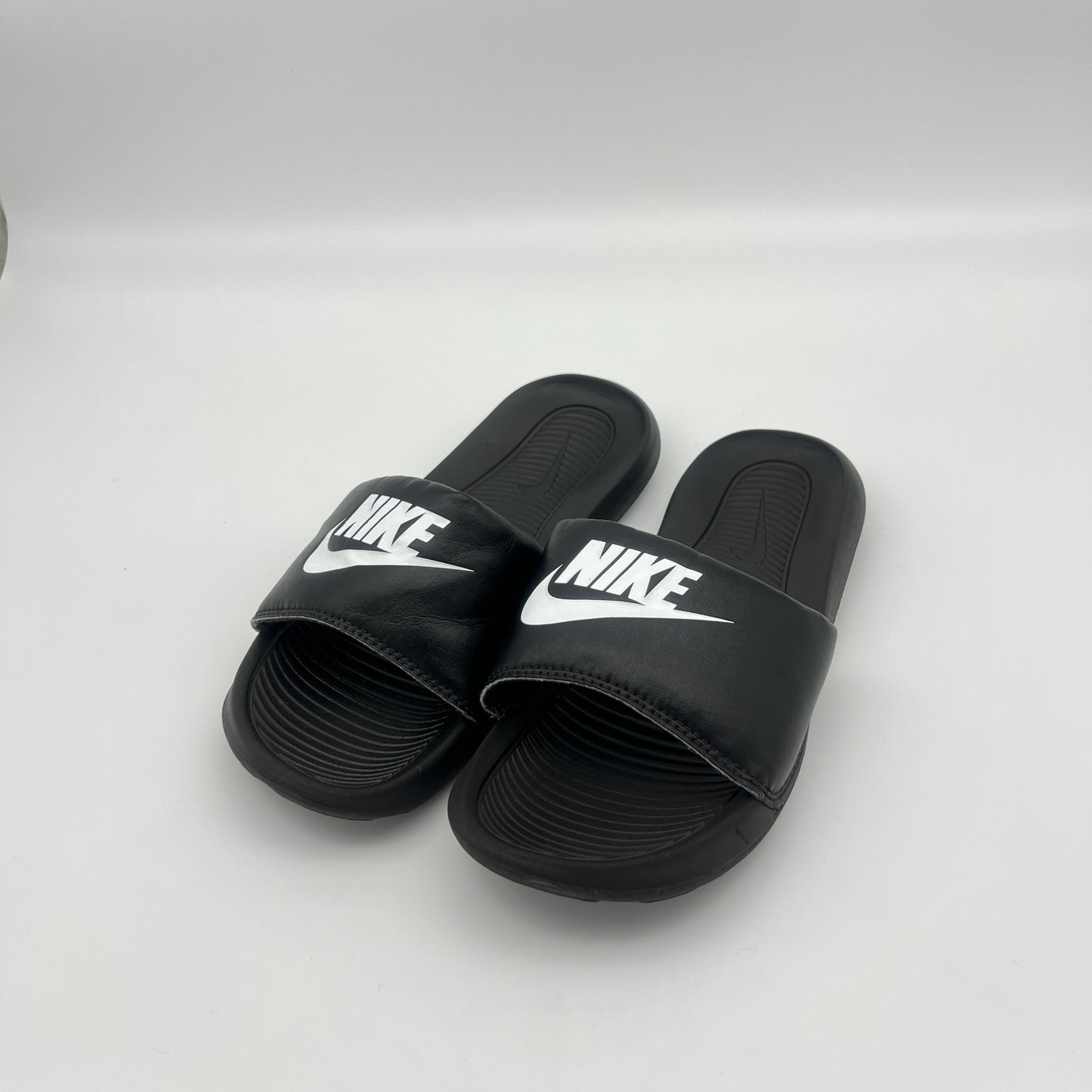 Black Nike slides on a white background