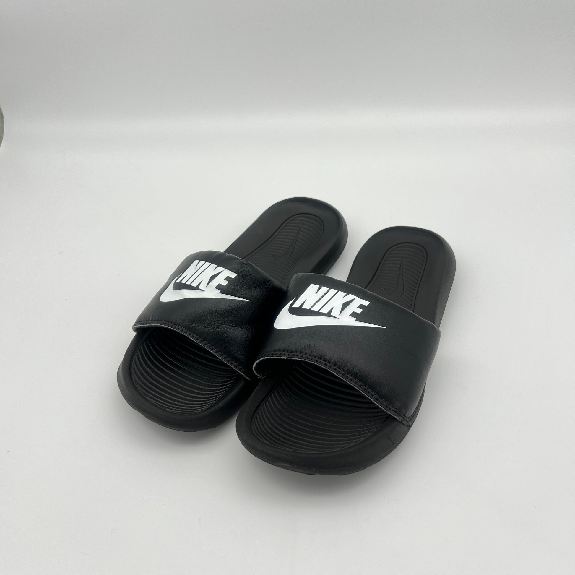 Black Nike slides on a white background