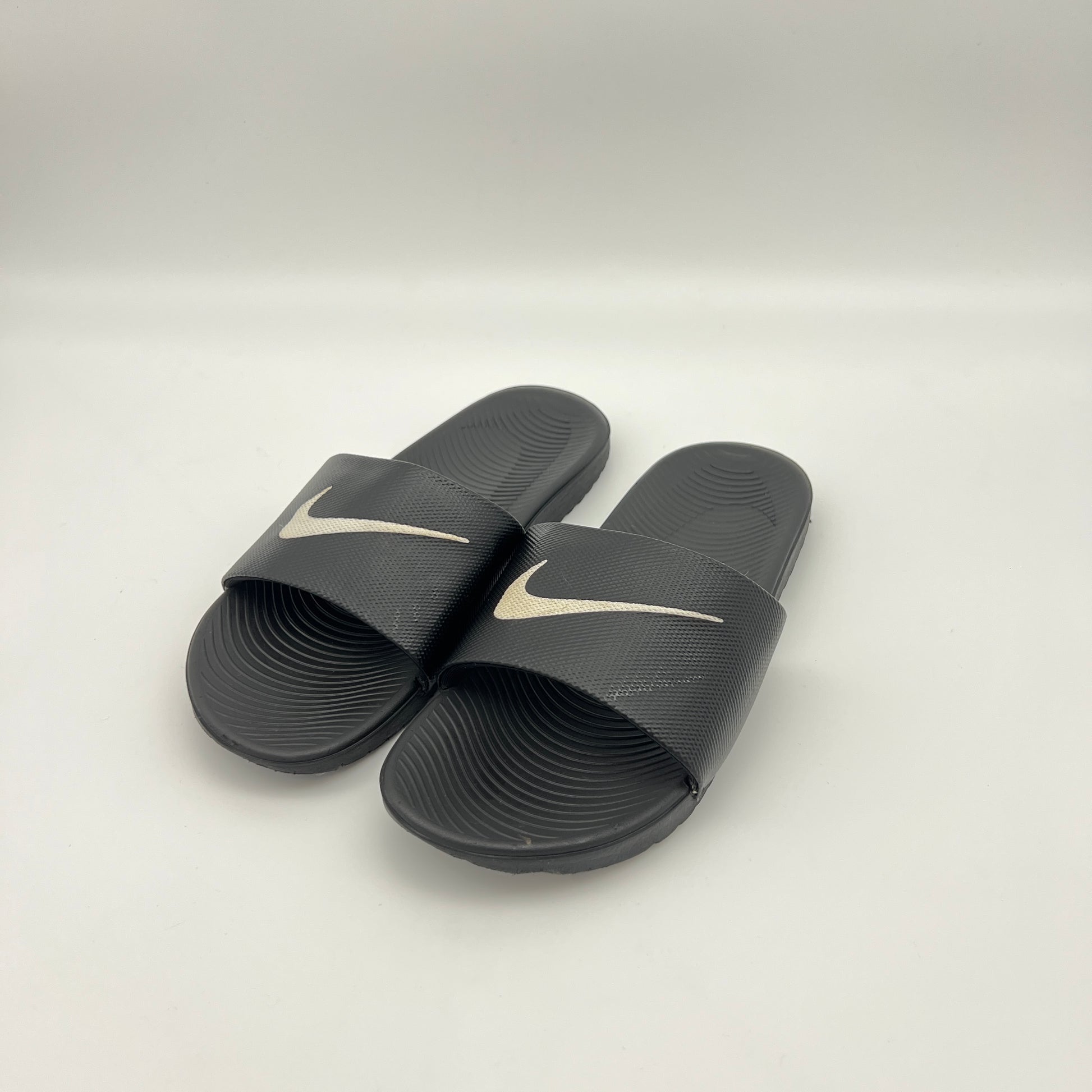 Pair of black slides with Nike logo on a white background