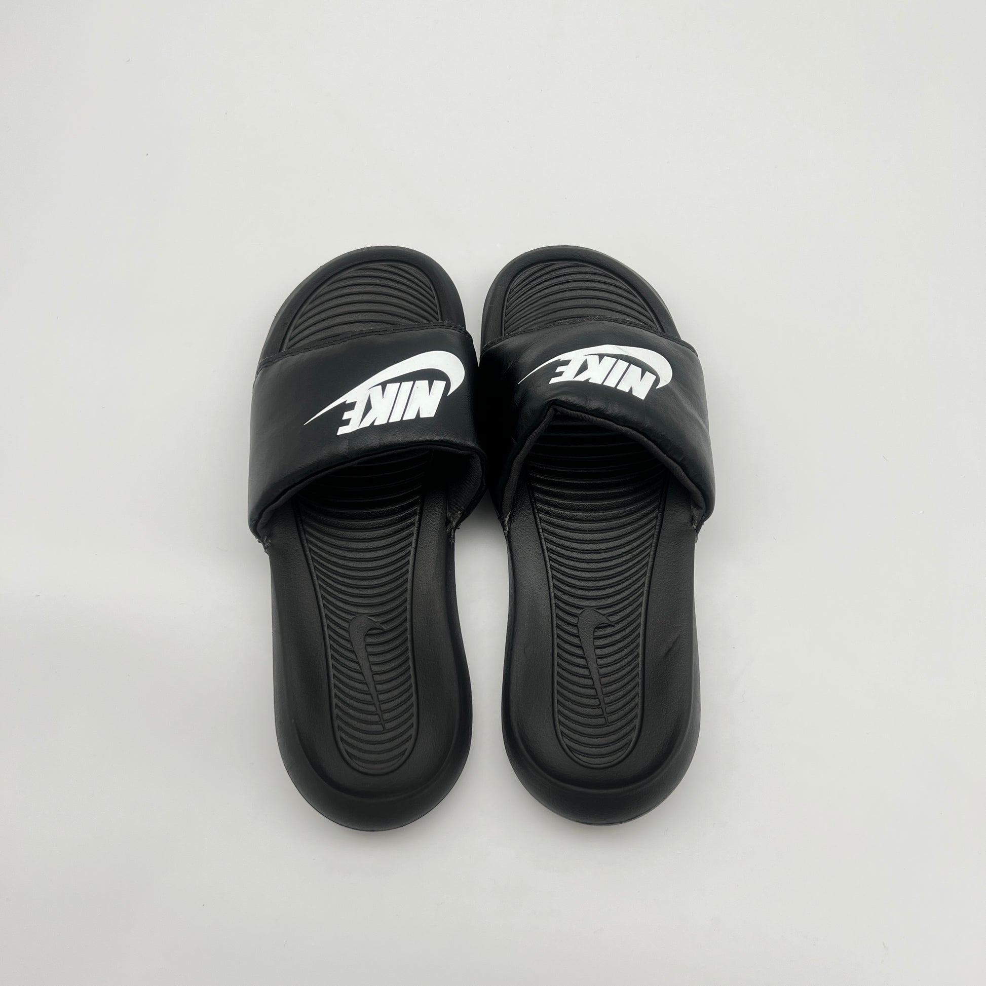 Black Nike slides on a light gray background