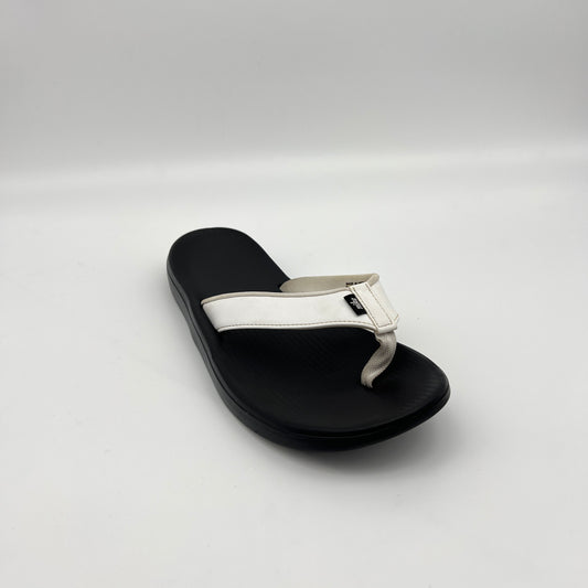Black sandal with a white strap on a light gray background