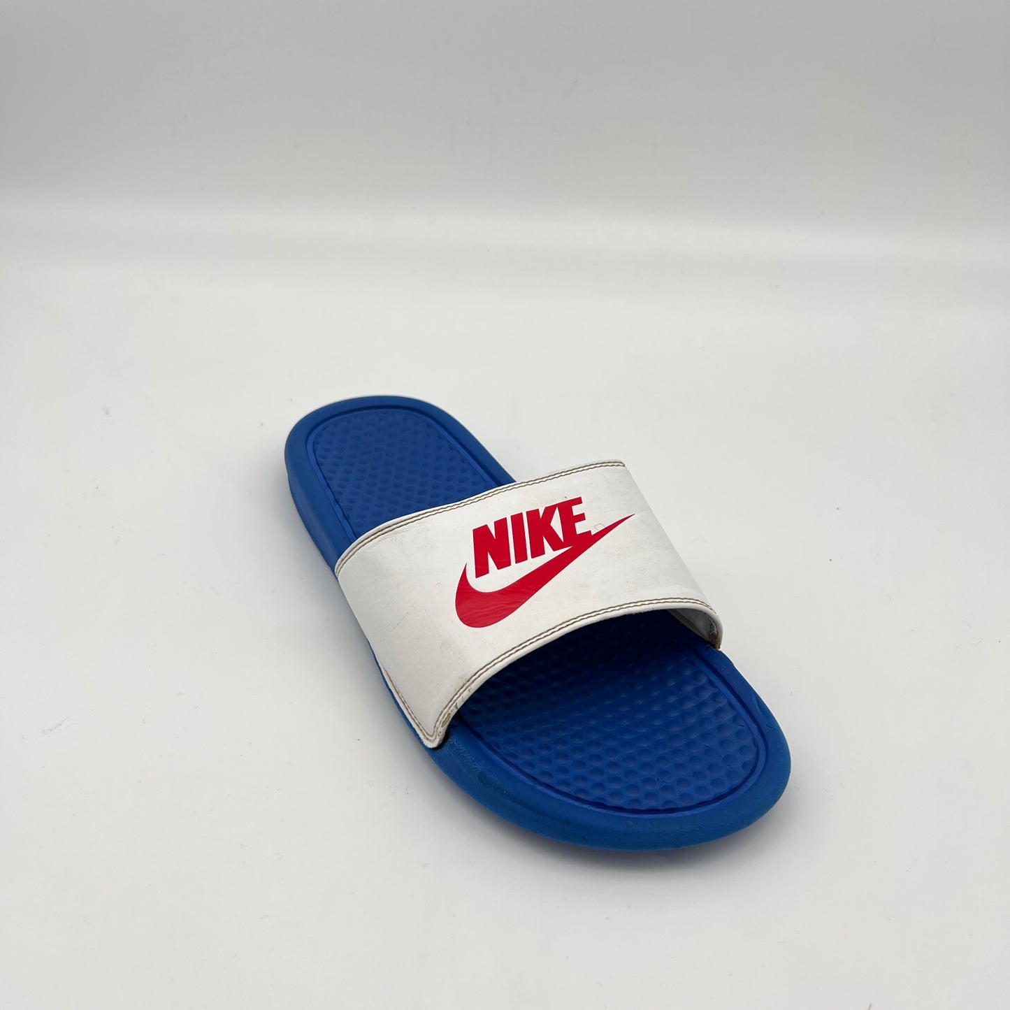 Blue and white Nike slide sandal on a light gray background