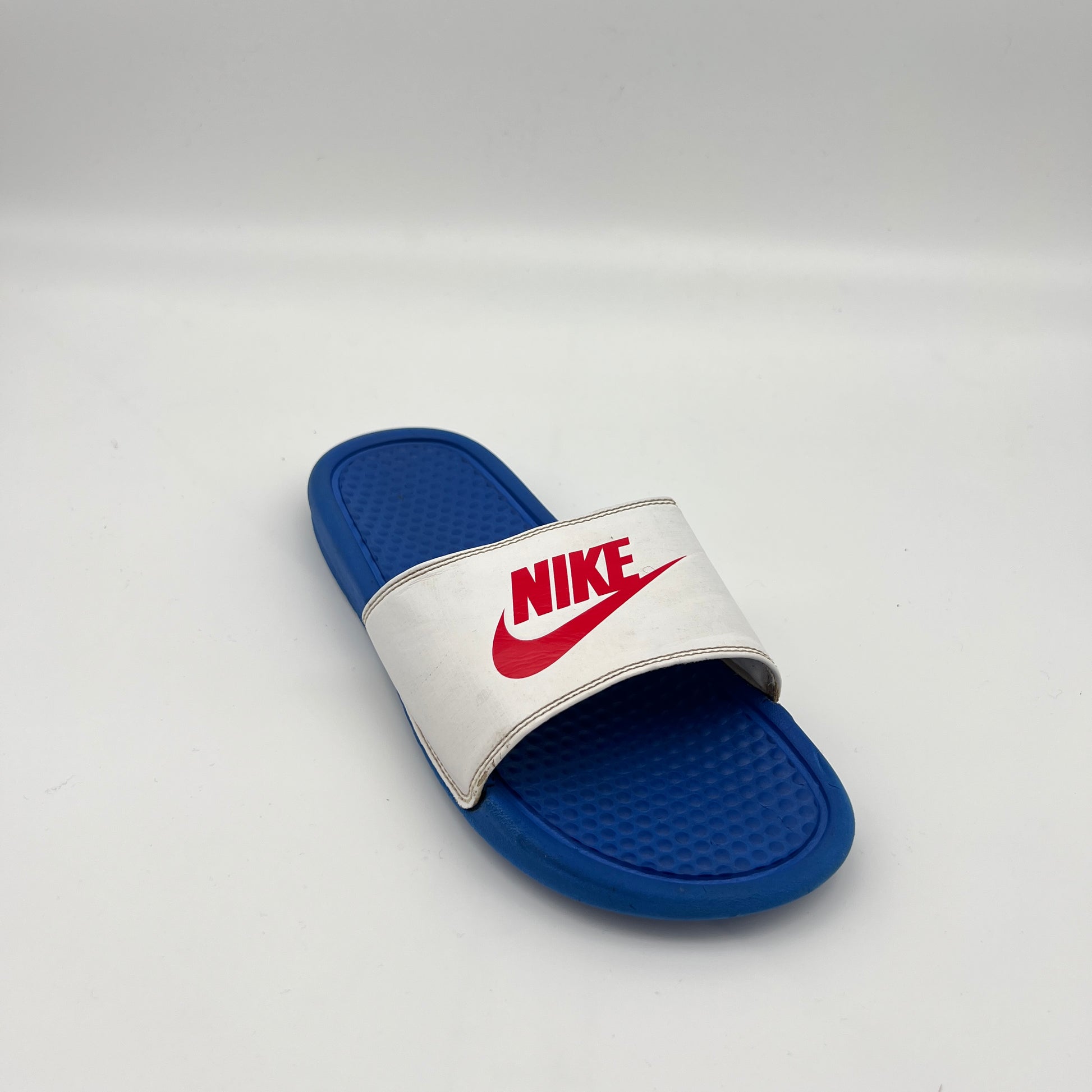 Blue and white Nike slide sandal on a light gray background