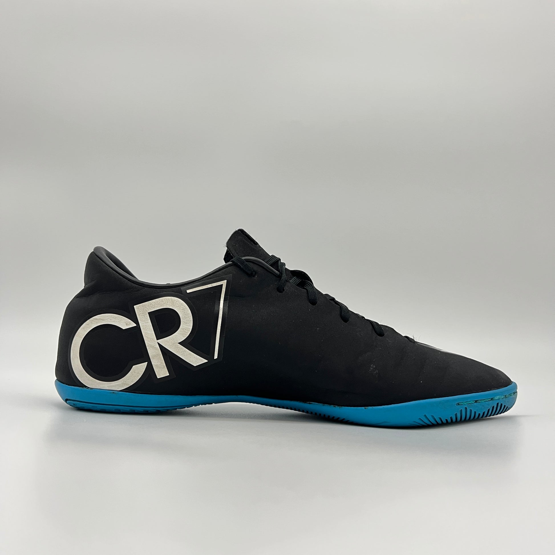 Black soccer shoe with blue sole and 'CR' logo on a gray background