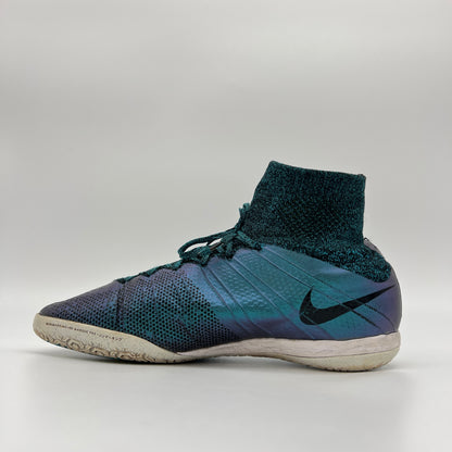 Side profile of an iridescent Squadron Blue Nike MercurialX Proximo IC indoor soccer shoe with a black Nike swoosh and a high-top Flyknit sock collar.
