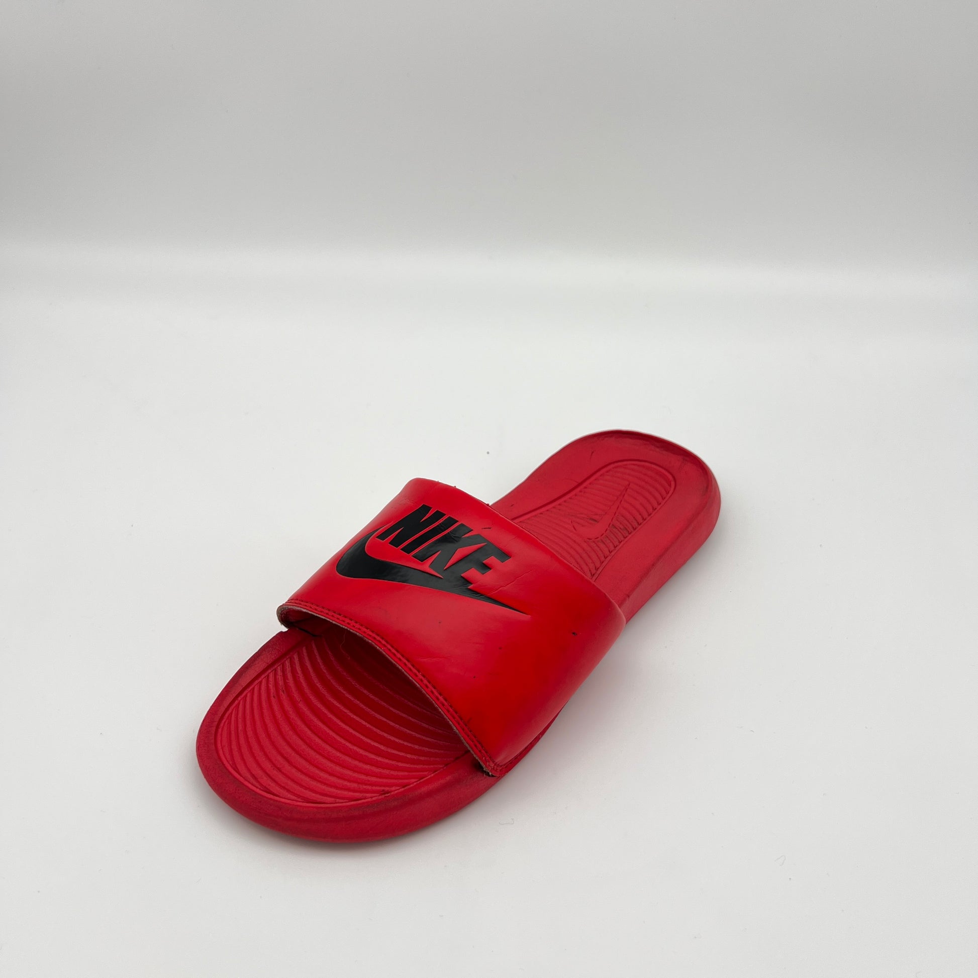 Close-up of the textured, contoured footbed and padded strap of the Nike Victori One slide in red