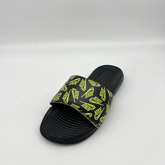 Black slide sandal with yellow Nike logo pattern on a white background