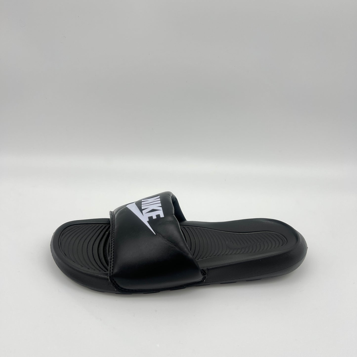 Black slide sandal with Nike logo on a light gray background