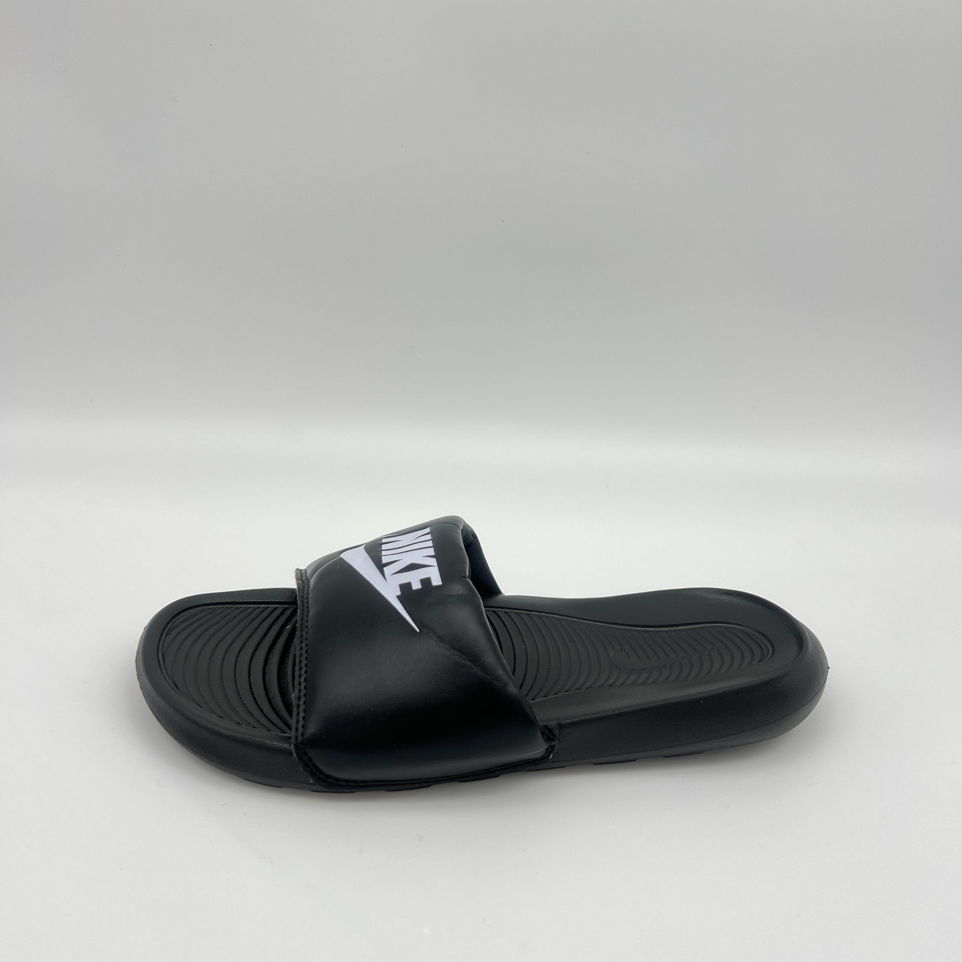 Black slide sandal with Nike logo on a light gray background
