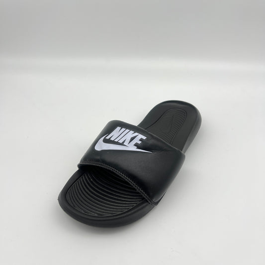A black Nike Victori One slide with a white Nike logo on the padded strap, displayed on a clean white background.
