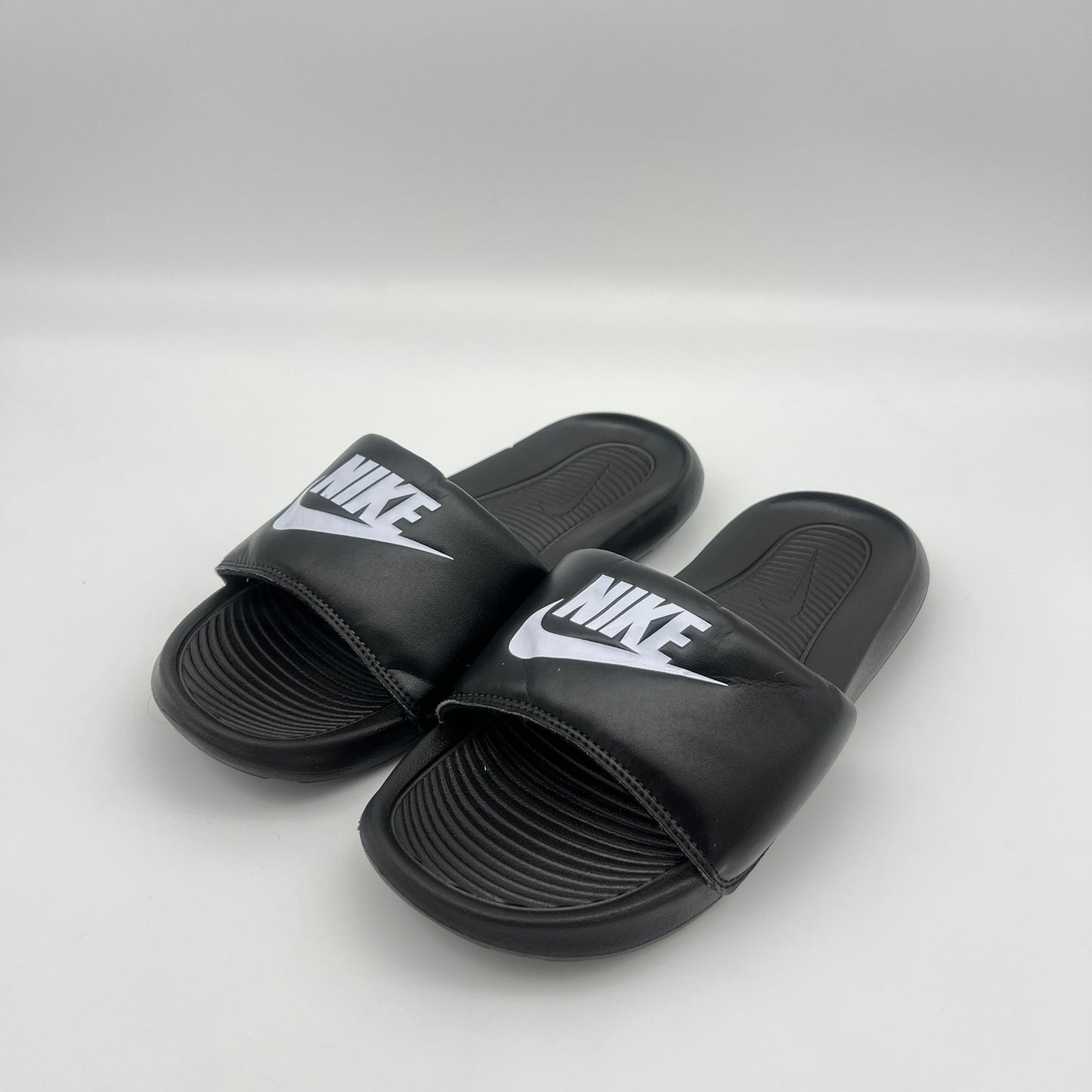 Black Nike slides on a light gray background