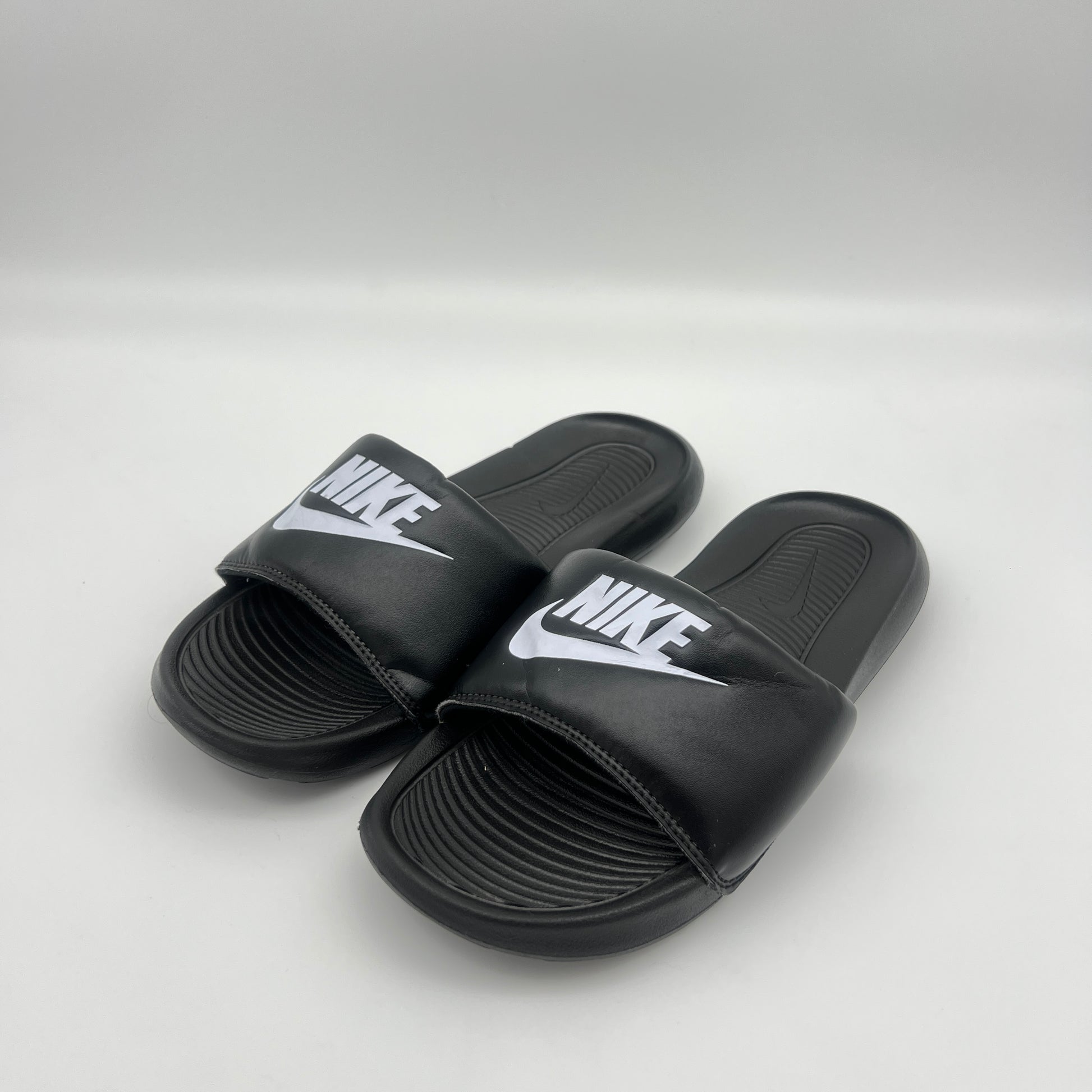 Black Nike slides on a light gray background