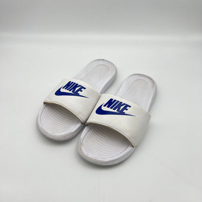 White Nike slides with blue logo on a white background