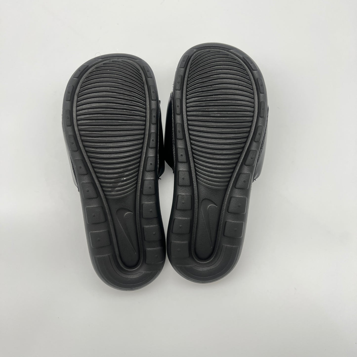 Black sandals with textured soles on a light gray background