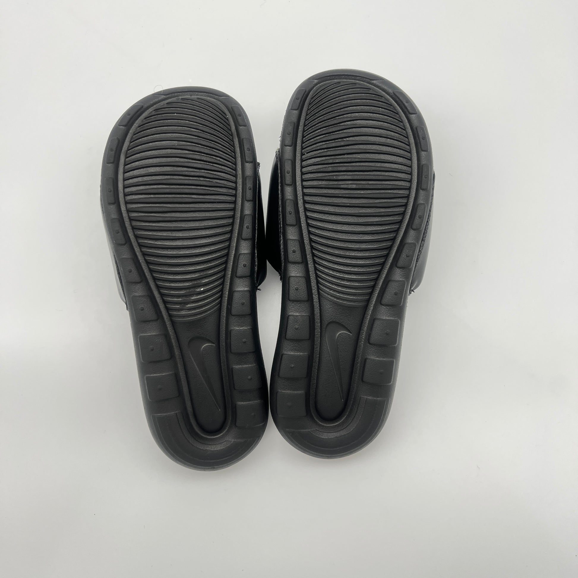 Black sandals with textured soles on a light gray background