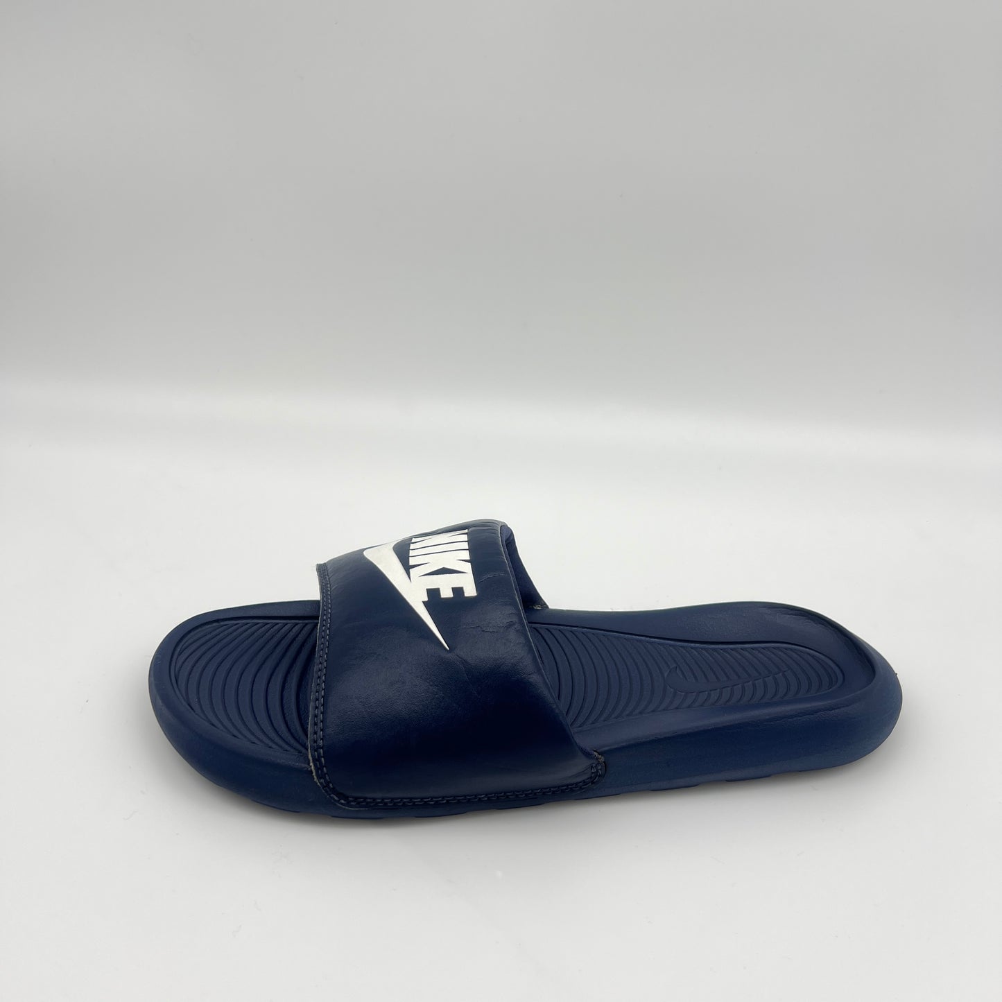 Navy blue slide sandal with Nike logo on a white background