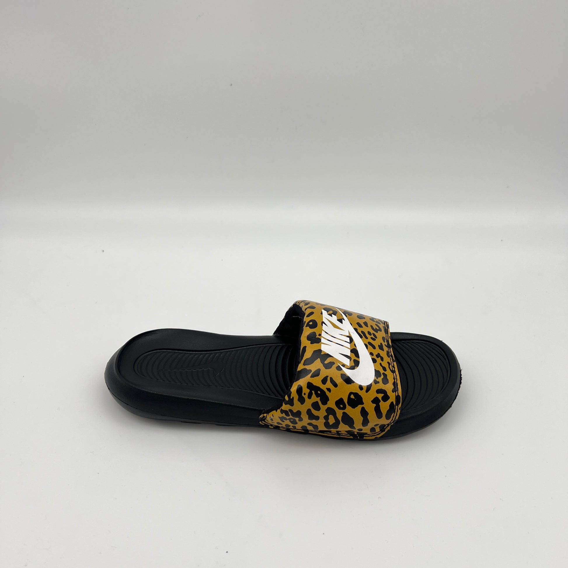 Nike Victori One women's slide sandal with leopard print strap and white Nike logo on a black footbed