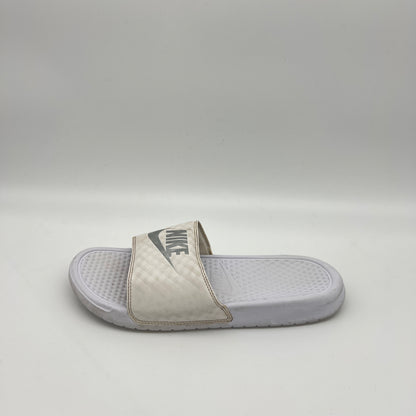 A single white Nike Benassi JDI slide sandal featuring a metallic silver Nike logo on a white checkered-patterned strap and a textured white footbed.