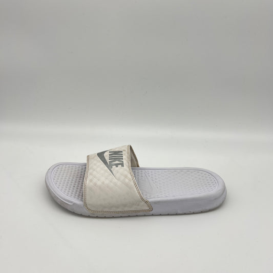 A single white Nike Benassi JDI slide sandal featuring a metallic silver Nike logo on a white checkered-patterned strap and a textured white footbed.