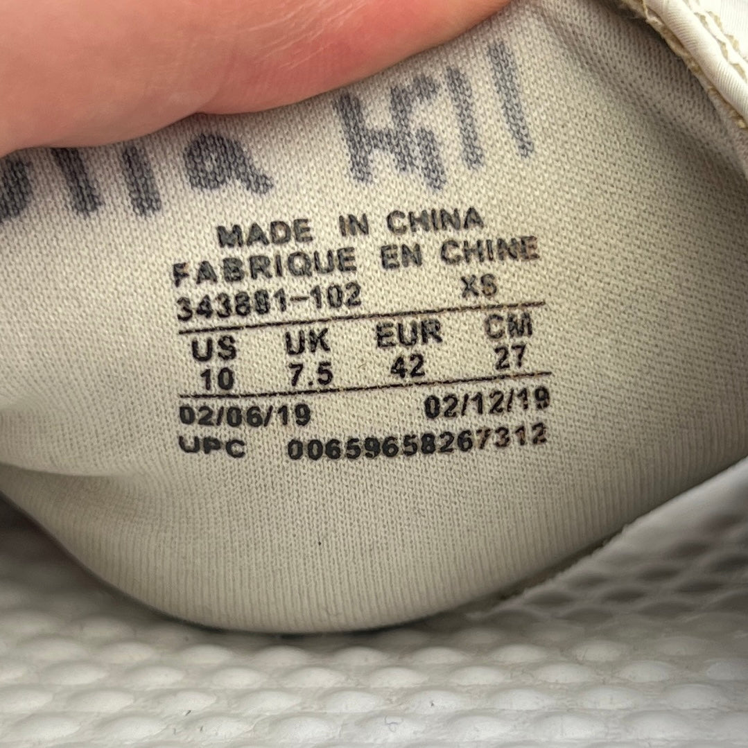 A single white Nike Benassi JDI slide sandal featuring a metallic silver Nike logo on a white checkered-patterned strap and a textured white footbed.