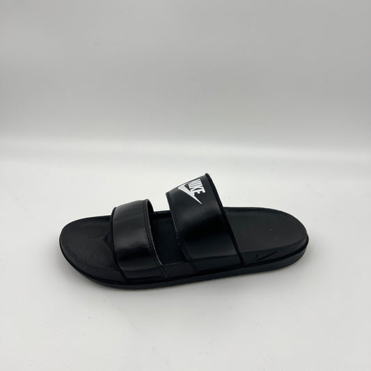 A side-profile view of a black Nike Offcourt Duo slide sandal with two parallel synthetic straps, a white Nike wordmark on the top strap, and a contoured footbed
