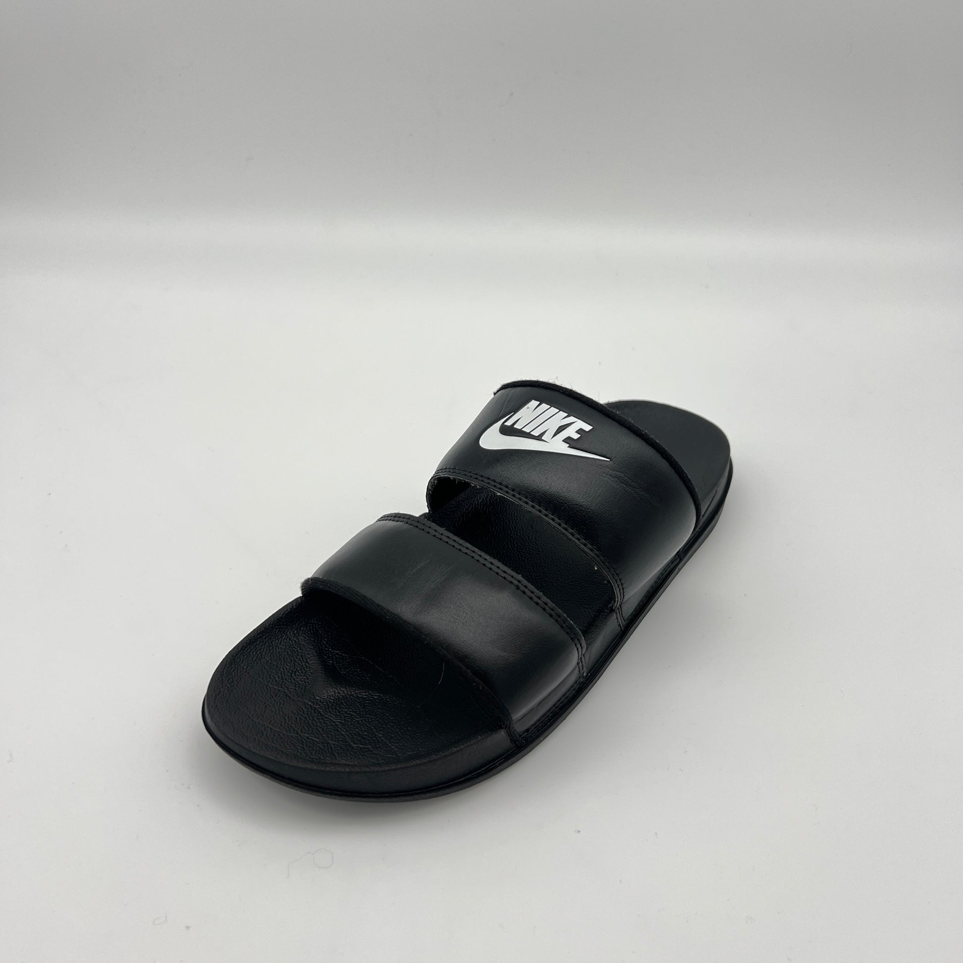 Black Nike sandal on a light gray background