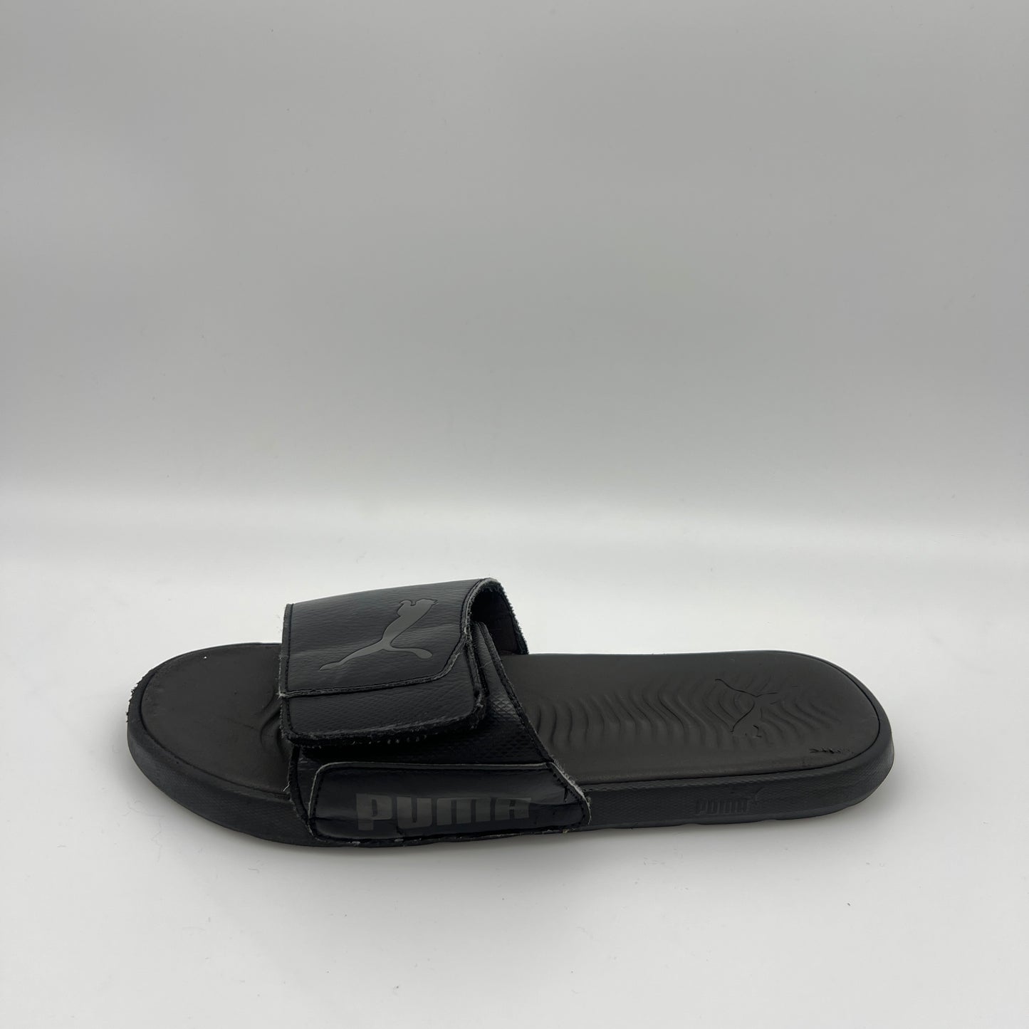 Puma Cool Cat 2.0 all-black men's slide sandal with adjustable logo strap and textured cushioned footbed.