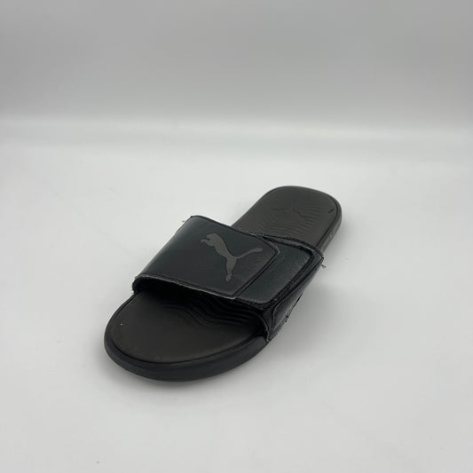Black slide sandal with Puma logo on a light gray background