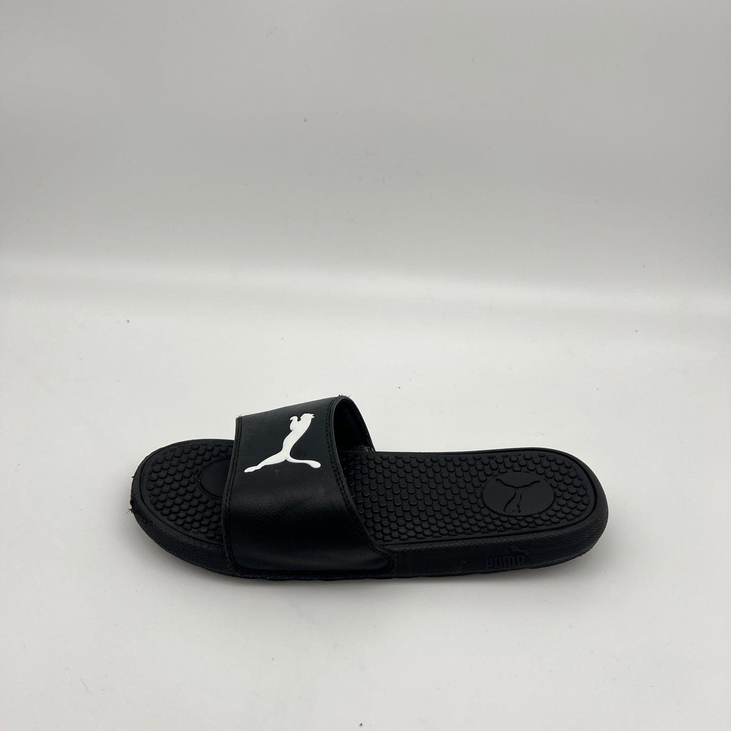 A single black PUMA Cool Cat Sport slide sandal featuring a prominent white jumping cat logo on the strap and a textured footbed on a white background.