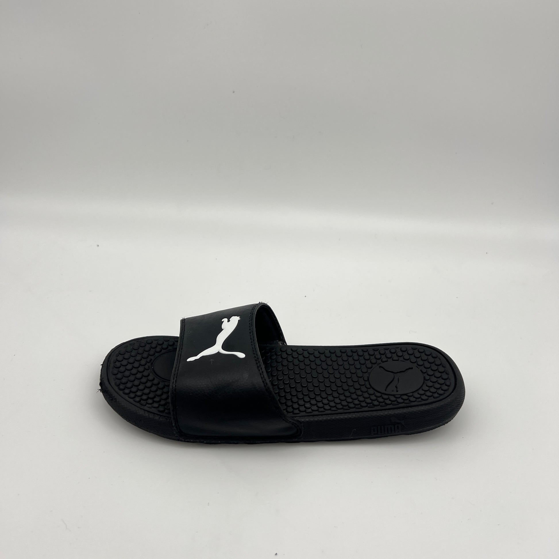 A single black PUMA Cool Cat Sport slide sandal featuring a prominent white jumping cat logo on the strap and a textured footbed on a white background.