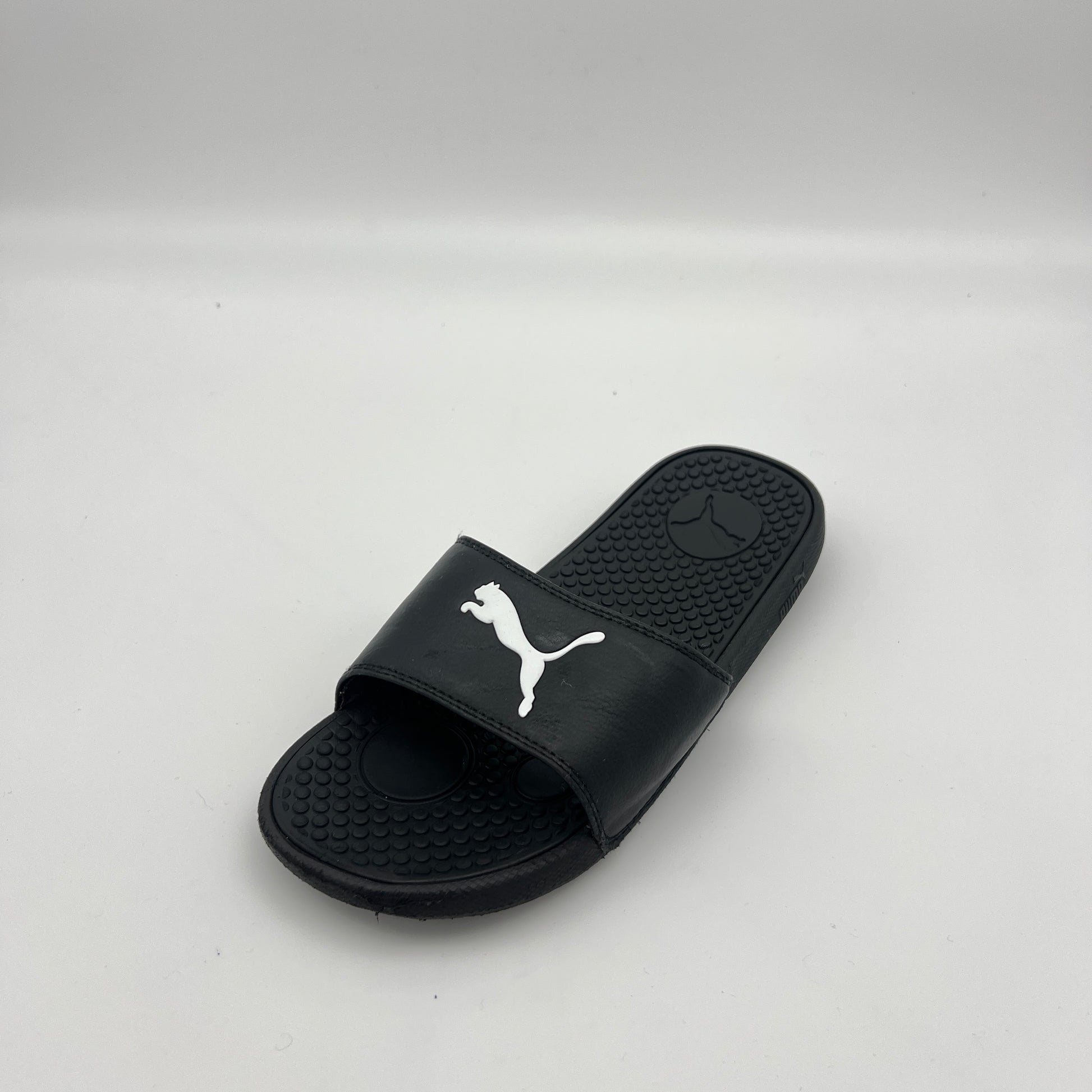 A single black PUMA Cool Cat Sport slide sandal featuring a prominent white jumping cat logo on the strap and a textured footbed on a white background.