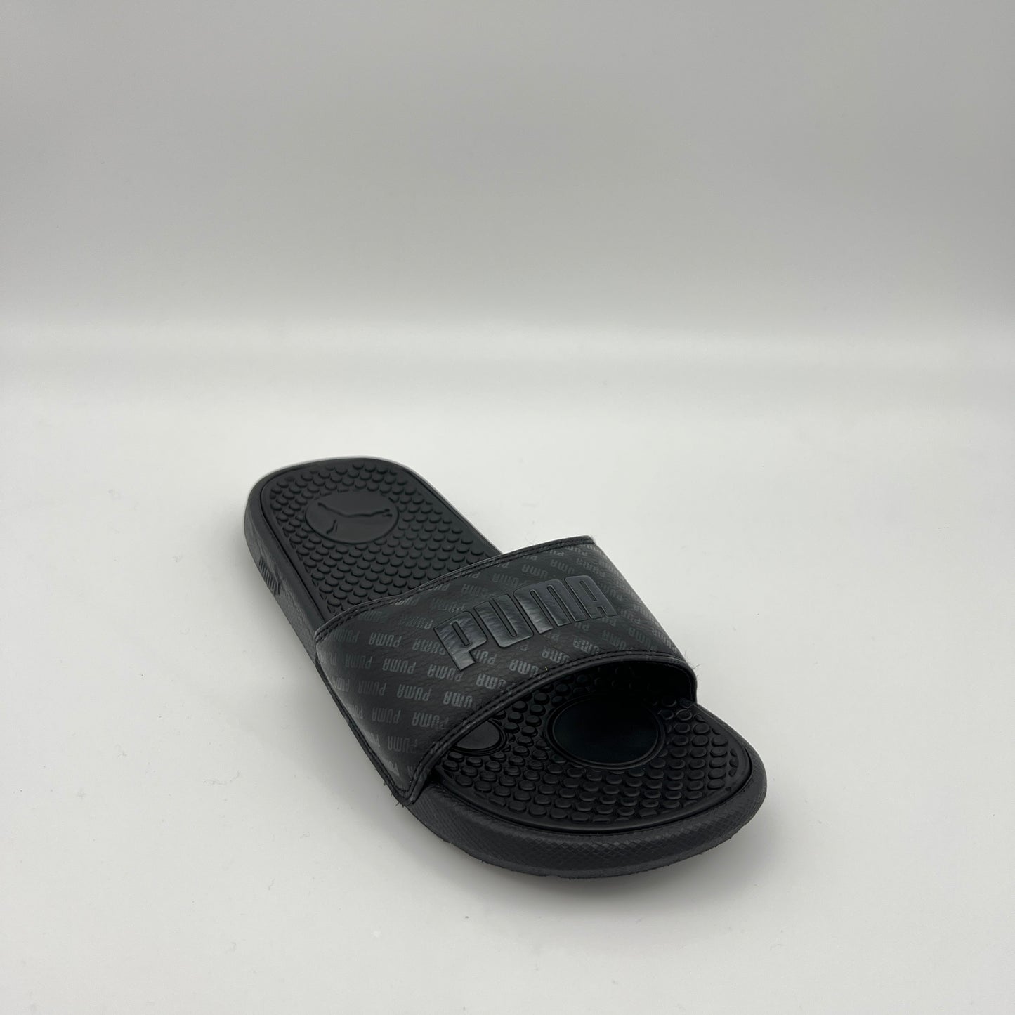 Black slide sandal with Puma logo on a light gray background