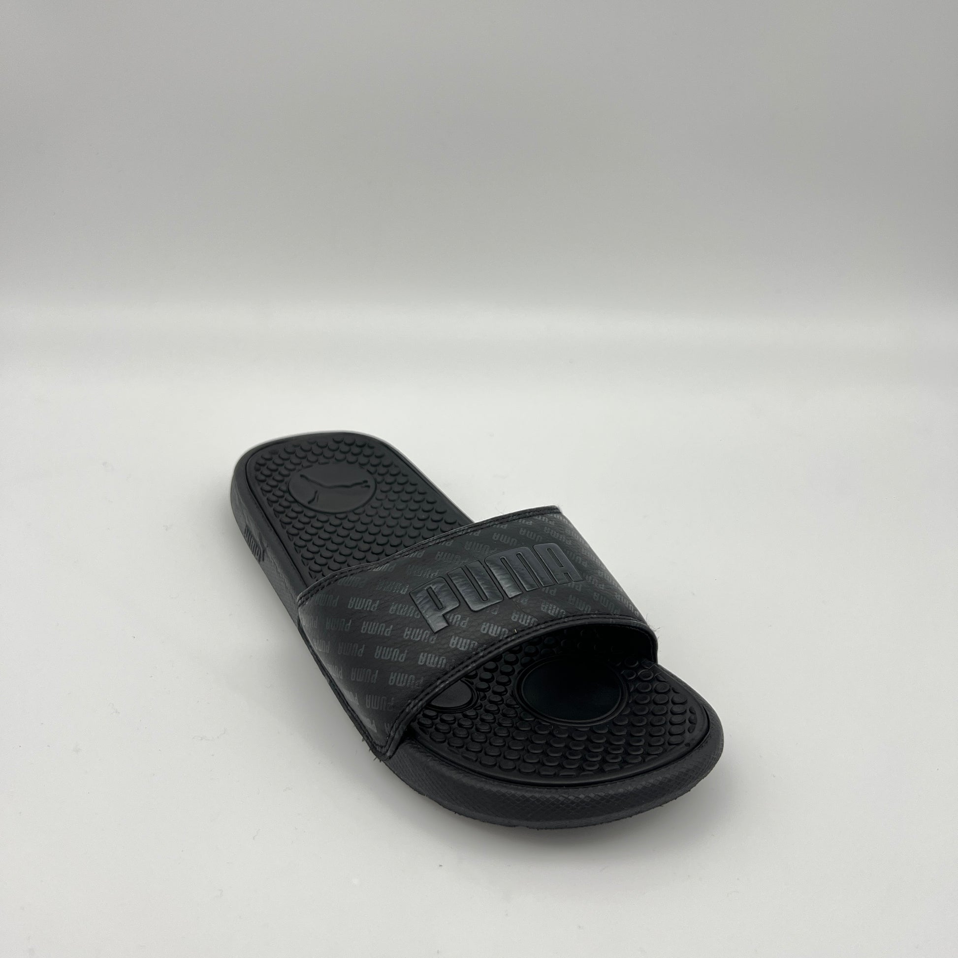 Black slide sandal with Puma logo on a light gray background