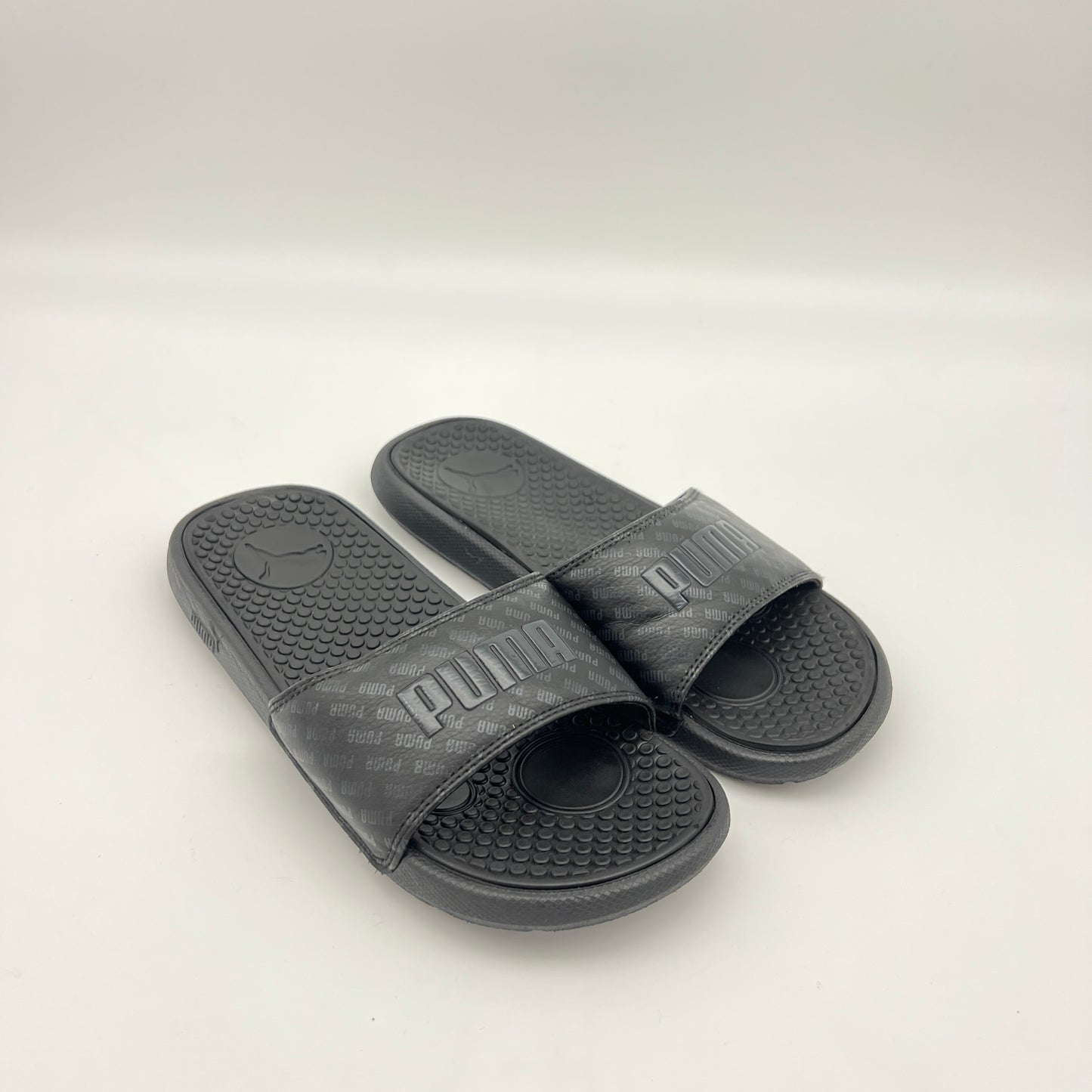 Pair of black Puma slides on a light gray background