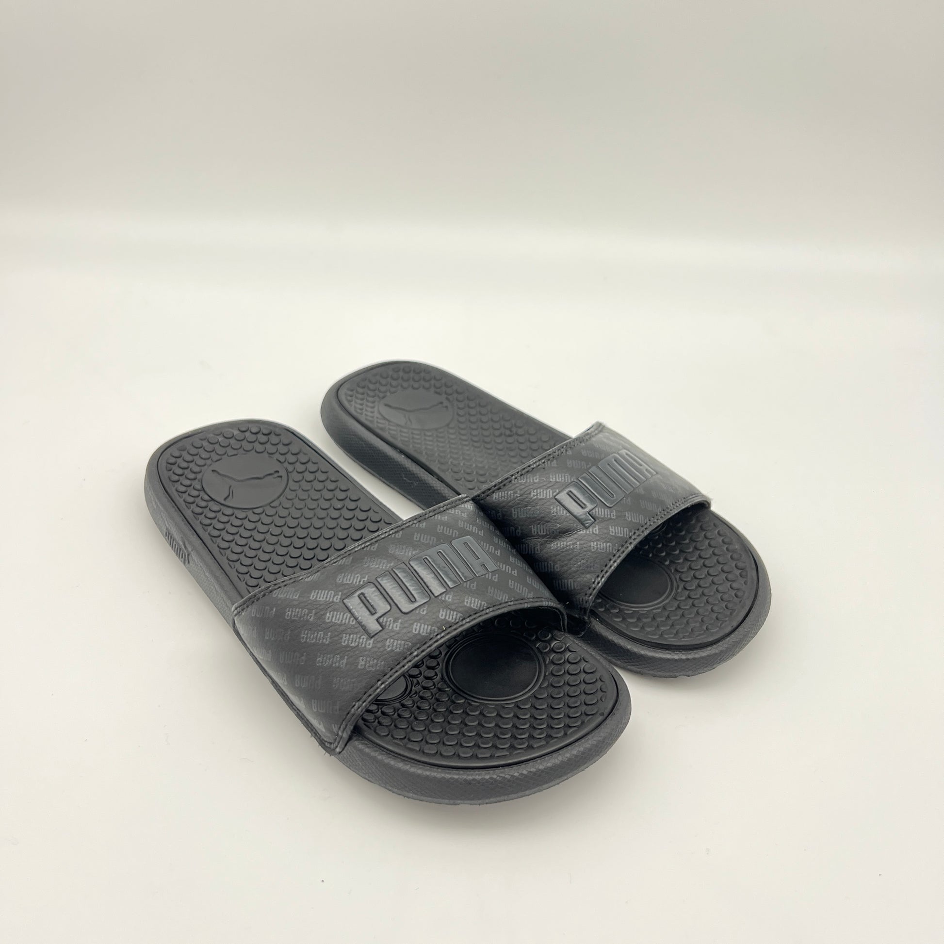 Pair of black Puma slides on a light gray background