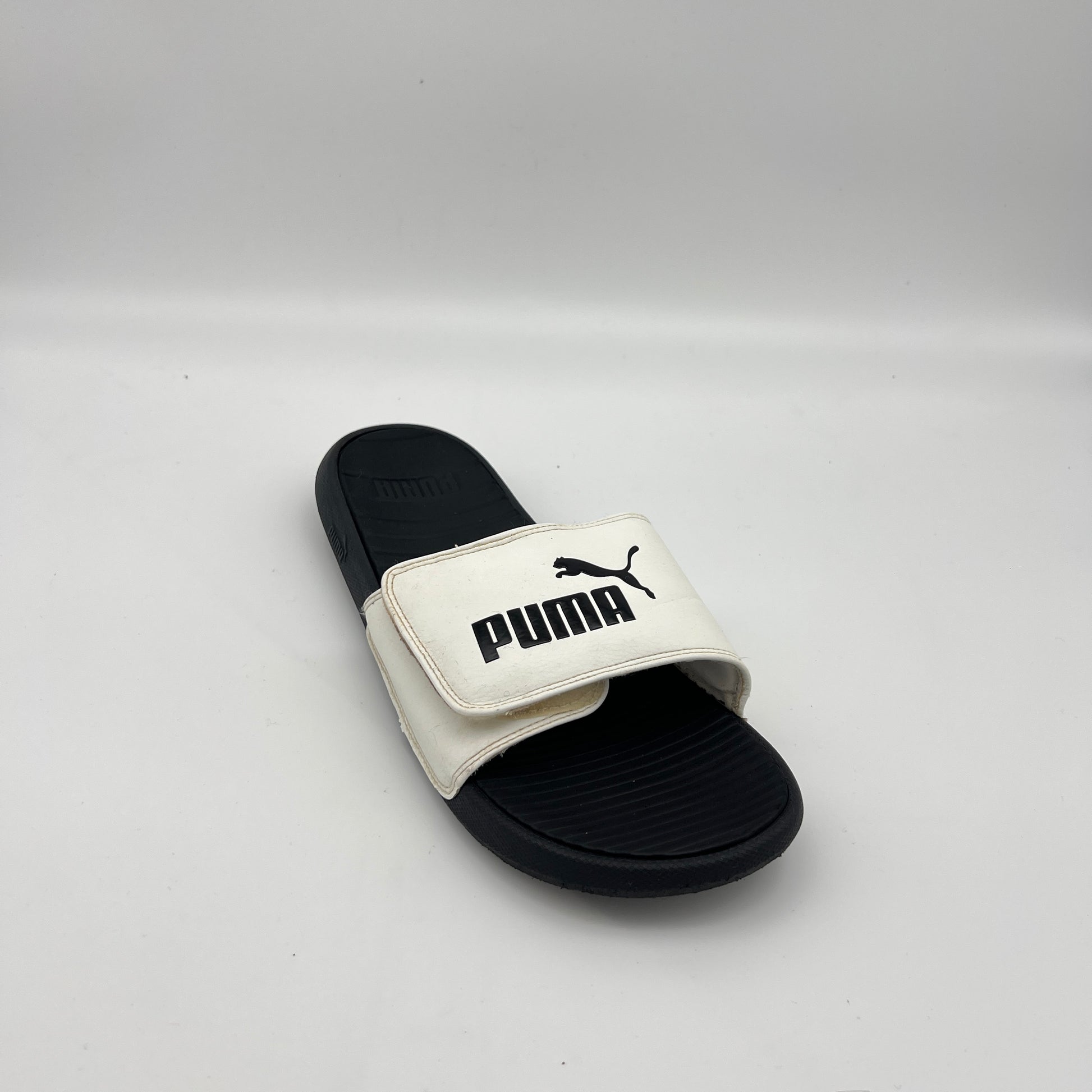 Men's PUMA athletic slides with a white adjustable logo strap and black textured sole.