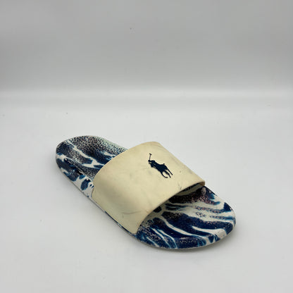 Side view of Ralph Lauren pool slides featuring a navy marble-patterned footbed and a white synthetic strap with a navy embroidered pony.